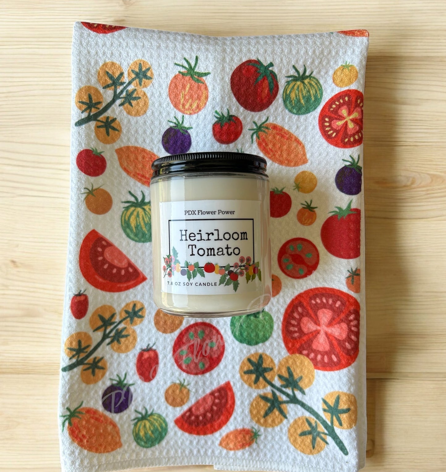 Candle with 'Heirloom Tomato' label on a towel with tomato pattern, PDX Flower Power branding.